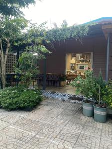 eine Terrasse mit Topfpflanzen und ein Haus in der Unterkunft Lọ Lem Homestay in Vĩnh Long