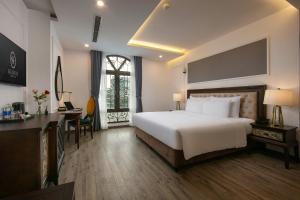 a bedroom with a bed and a desk and a window at Gloud Hotel in Hanoi