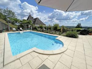 una piscina en un patio con sombrilla en Le pigeonnier, en Trémolat