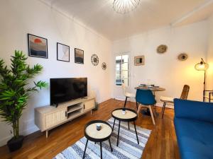 ein Wohnzimmer mit einem TV und einem blauen Sofa in der Unterkunft Charmants F2 6min du T6 - Bail Mobilité in Châtillon