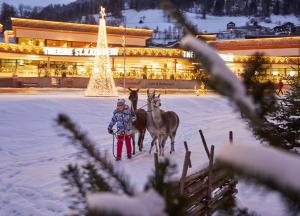 a person walking two horses in the snow in front of a building at Gasthof-Pension Alt Kirchheim in Bad Kleinkirchheim