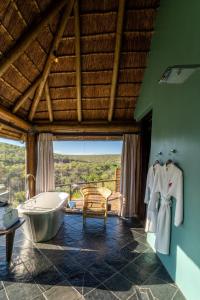 a bathroom with a tub and a chair and a window at Sediba Luxury Safari Lodge in Welgevonden Game Reserve