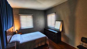 Guest House in Sucre في سوكر: غرفة نوم بسرير وخزانة ونوافذ