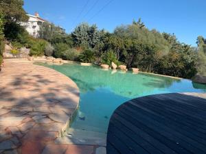 a swimming pool with blue water in a yard at Chambre cosy Aphrodite avec accès a la piscine et au jacuzzi in Porto-Vecchio