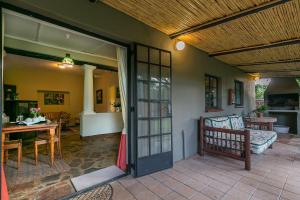 een patio met een tafel en een bank en een tafel en stoelen bij La Bastide Guest House in Hartbeespoort