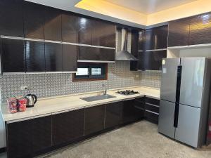 La cuisine est équipée de placards noirs et d'un réfrigérateur en acier inoxydable. dans l'établissement S Pool Villa Clark 天天别墅酒店, à Ángeles