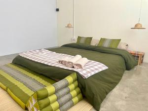 Una gran cama verde con toallas encima. en Baan KhaoSoi - Private room in a rooftop hostel 2nd floor, en Khlong San