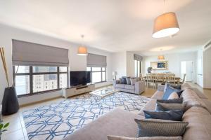 a living room with a couch and a tv at Stunning Marina & Sea View 4 Bedroom Apartment, Murjan 6 Jumeriah Beach in Dubai