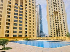 a swimming pool in the middle of two tall buildings at Stunning Marina & Sea View 4 Bedroom Apartment, Murjan 6 Jumeriah Beach in Dubai