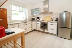 特拉森海德Ferienhaushälfte Hubertus的配有白色橱柜和不锈钢器具的厨房 更多15张照片