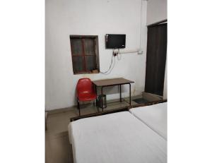um quarto com uma cadeira vermelha, uma mesa e uma televisão em Vineet Hotel,Prayagraj em Prayagraj