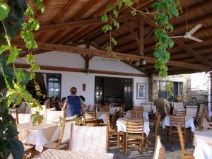 a man standing in a restaurant with tables and chairs at Vrahos Studios in Kionia