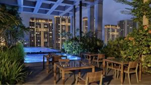 Un patio con mesas y sillas y una piscina. en Revo, Aurora-Pavilion 22, en Kuala Lumpur