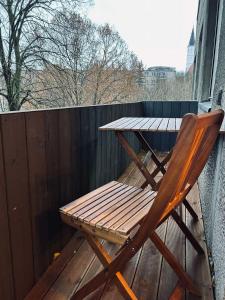 einen Holzstuhl auf einem Balkon mit einem Tisch in der Unterkunft Sun Clock Apartment in Šiauliai