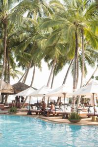 a pool with palm trees and people sitting on lounge chairs at Angel Beach Unawatuna in Unawatuna