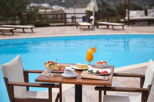 a table with food on it next to a pool at Amorgion Village in Katapola