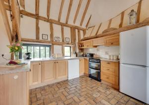 a large kitchen with white appliances and wooden cabinets at Tithe Barn at Wattisham Hall in Wattisham