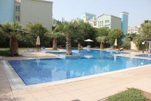 a large swimming pool with palm trees and buildings at Brand New Cozy Studio Apatrtment in Dubai