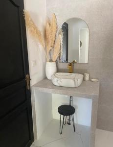 ein Badezimmer mit einem Waschbecken, einem Spiegel und einem Stuhl in der Unterkunft La tanière in Les Brugassières
