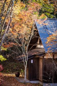 a tree next to a house with a blue roof at Villa Iizuna Plateau -飯綱高原の山荘- in Nagano