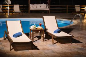 two chairs and a table next to a swimming pool at Amorgion Village in Katapola