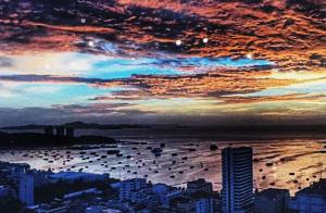 a sunset over a city with boats in the water at The Base Infinity in Pattaya Central