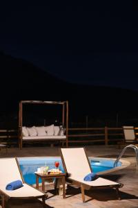 two chairs and a table next to a pool at Amorgion Village in Katapola