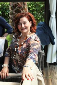 a woman sitting on a bench smiles at the camera at Palazzo Scavone in Palermo