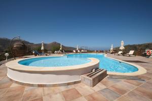 a swimming pool in a resort with chairs and tables at Amorgion Village in Katapola