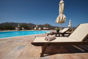 a pool with lounge chairs and an umbrella at Amorgion Village in Katapola