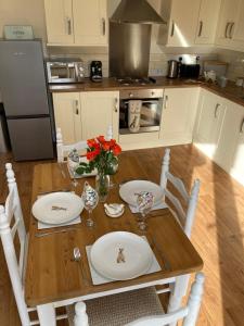 a kitchen with a wooden table with plates and flowers on it at The Stables in Metheringham