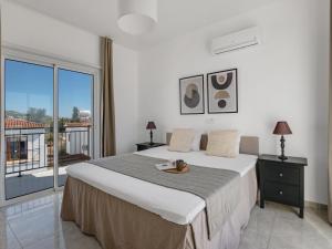 a bedroom with a large bed and a balcony at Sanders White Mountains Pool Villas in Paphos City