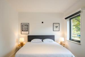 una camera da letto con un grande letto bianco con due lampade di Charmant Gents app met alle comfort en vlot bereikbaar a Gand