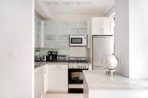 a white kitchen with white cabinets and appliances at Cozy Studio Apartment in New York