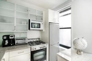 a white kitchen with a stove and a refrigerator at Cozy Studio Apartment in New York