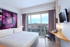 a hotel room with a bed and a large window at favehotel Solo Baru in Solo