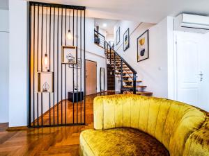 uma sala de estar com um sofá amarelo e uma escada em Lofty em Brcko