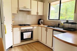 una cucina con mobili bianchi, un lavello e una stufa di Skyview Cottage a Leura