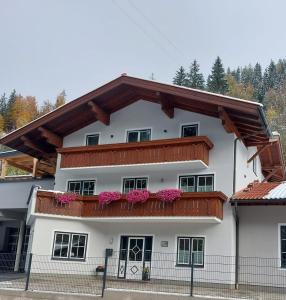 a white building with a balcony with pink flowers at Appartement Riepler in Wagrain