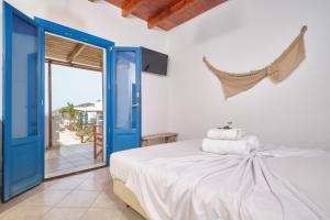 Schlafzimmer mit einem Bett mit blauen Türen und einem Balkon in der Unterkunft Amorgion Hotel in Katápola