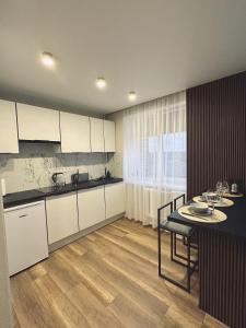 eine Küche mit weißen Schränken, einem Tisch und einem Esszimmer in der Unterkunft Vienibas Apartaments in Krāslava