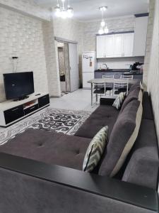 ein Wohnzimmer mit einem großen Sofa und einer Küche in der Unterkunft Комфортная двухкомнатная квартира in Bischkek