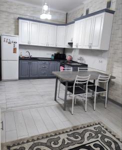eine Küche mit einem Tisch und Stühlen sowie einem Kühlschrank in der Unterkunft Комфортная двухкомнатная квартира in Bischkek