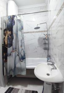 ein Bad mit einem Waschbecken und einem Duschvorhang in der Unterkunft Комфортная двухкомнатная квартира in Bischkek