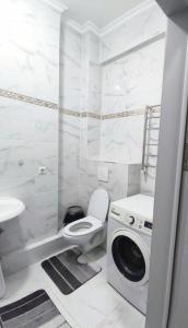 ein weißes Bad mit einem WC und einer Waschmaschine in der Unterkunft Комфортная двухкомнатная квартира in Bischkek