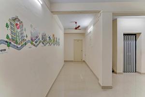 un couloir avec un mur blanc orné d'une fresque murale. dans l'établissement OYO Flagship 15148 Sky Pix Near Kasi Talkies, à Chennai