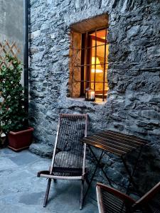 a wooden table and a chair in front of a stone building at Maison Bovet Mont Blanc in La Salle