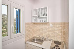 a kitchen with a sink and a window at Amorgion Village in Katapola +37 photos