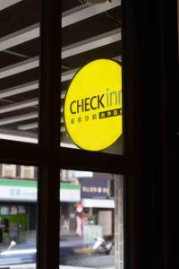 a yellow checkin sign is seen through a window at CHECK inn Taichung Ziyou in Taichung