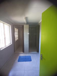 La salle de bains est pourvue d'une porte verte et d'un tapis bleu. dans l'établissement Prime Guest Inn, à Benoni